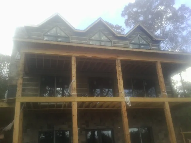 Dormers and porch framing on a large log home under construction — Roof Coating work by our crew in Pointblank