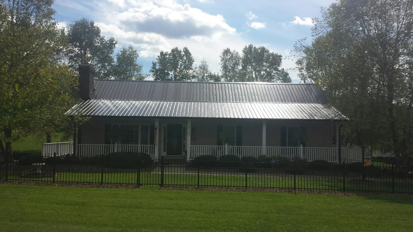 Gray metal roof on a brick ranch with a full width front porch — Gutter Guard Installation work by our crew in Pointblank
