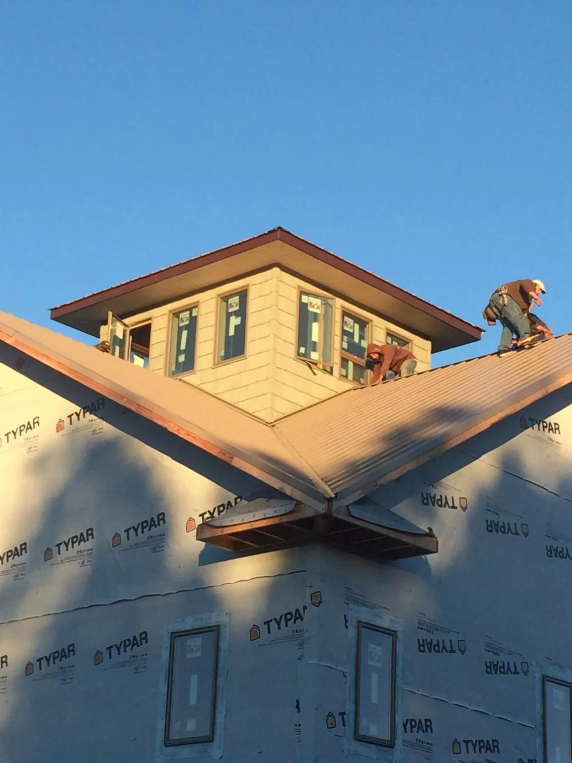 Roofers working around a rooftop cupola on a new metal roof at sunset — Roof Waterproofing in Pointblank by Roofing Brothers